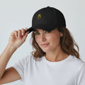 The Savage Mammoth Tab Khod structured black cap with yellow hand embroidery worn by a woman in a white t-shirt